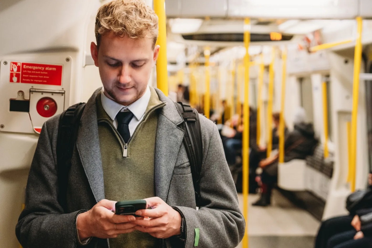 A man on a London Underground train, reading his phone